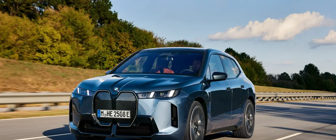 BMW iX xDrive60 photographed from the front three-quarter angle on a road