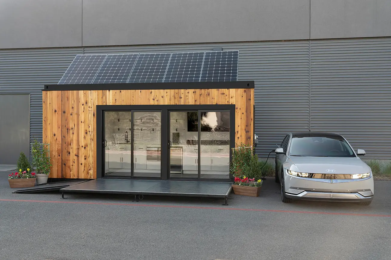 Carro elétrico a carregar numa wallbox doméstica junto a uma moradia com painéis solares no telhado