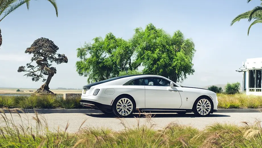 Rolls-Royce Spectre Series II side profile on a road, showing its two-door coupé shape