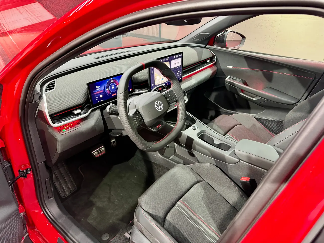 Interior do Volkswagen ID. Polo GTI com painel digital, ecrã central e bancos com padrão xadrez