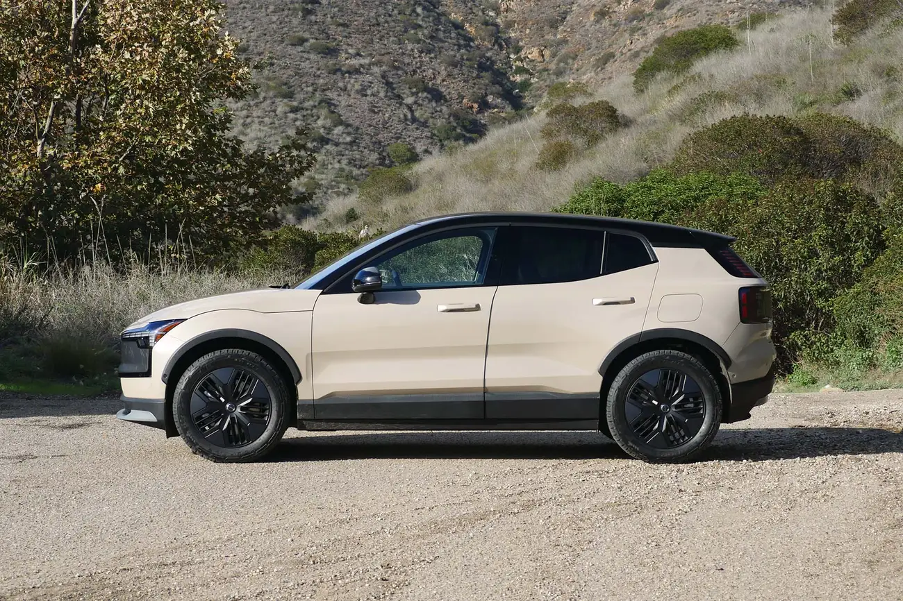 Volvo EX30 Cross Country de perfil numa estrada de terra, com as proteções de plástico preto nas cavas das rodas